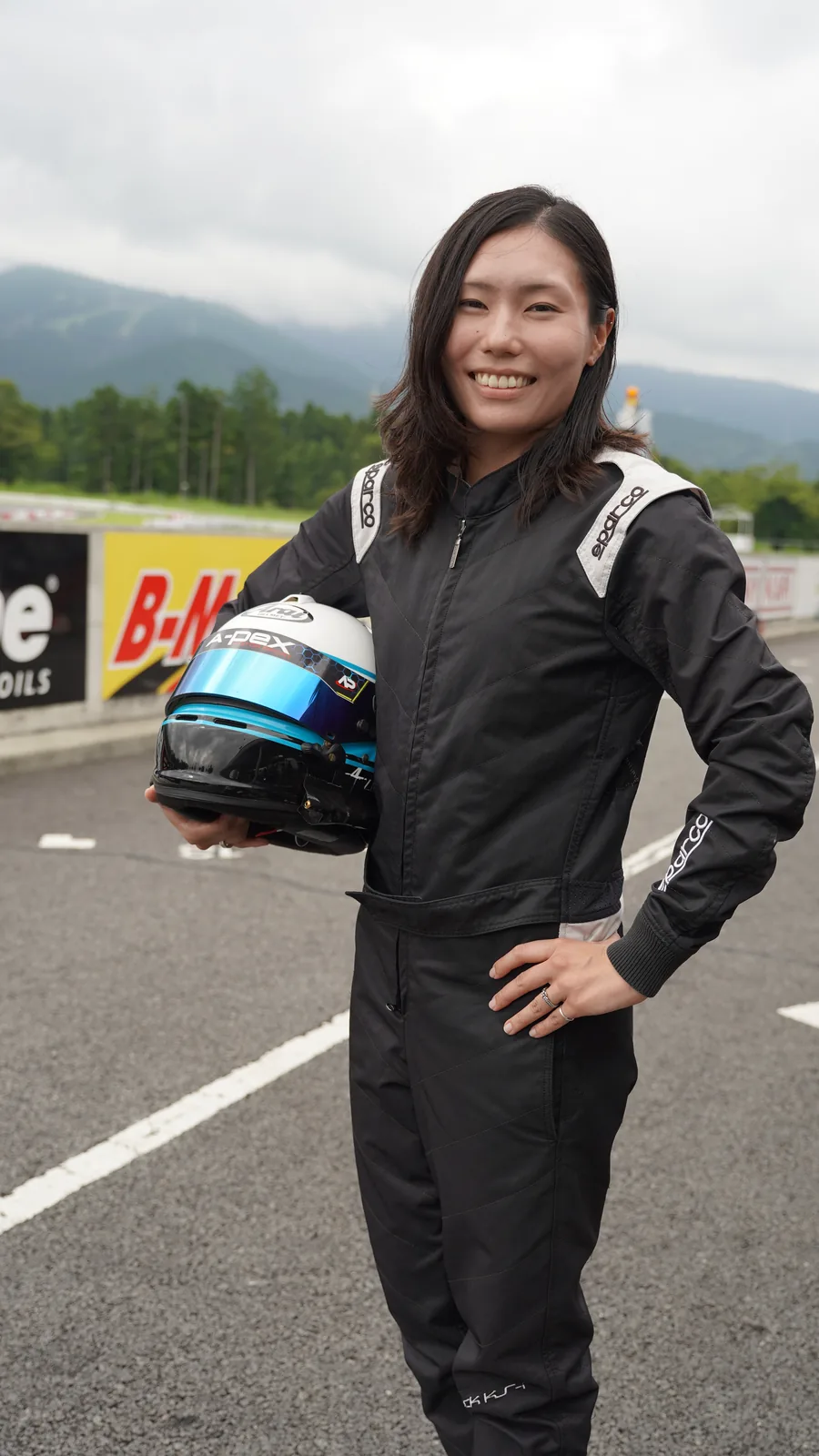 ヘルメットを手に、サーキットで。